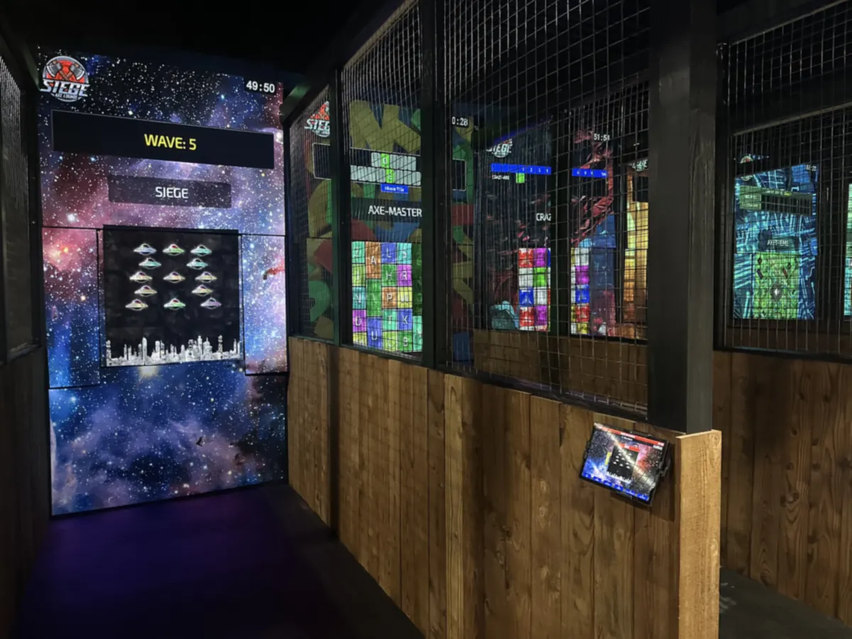 A projected arcade-style game lit on an axe lane board, with wire mesh between the lanes