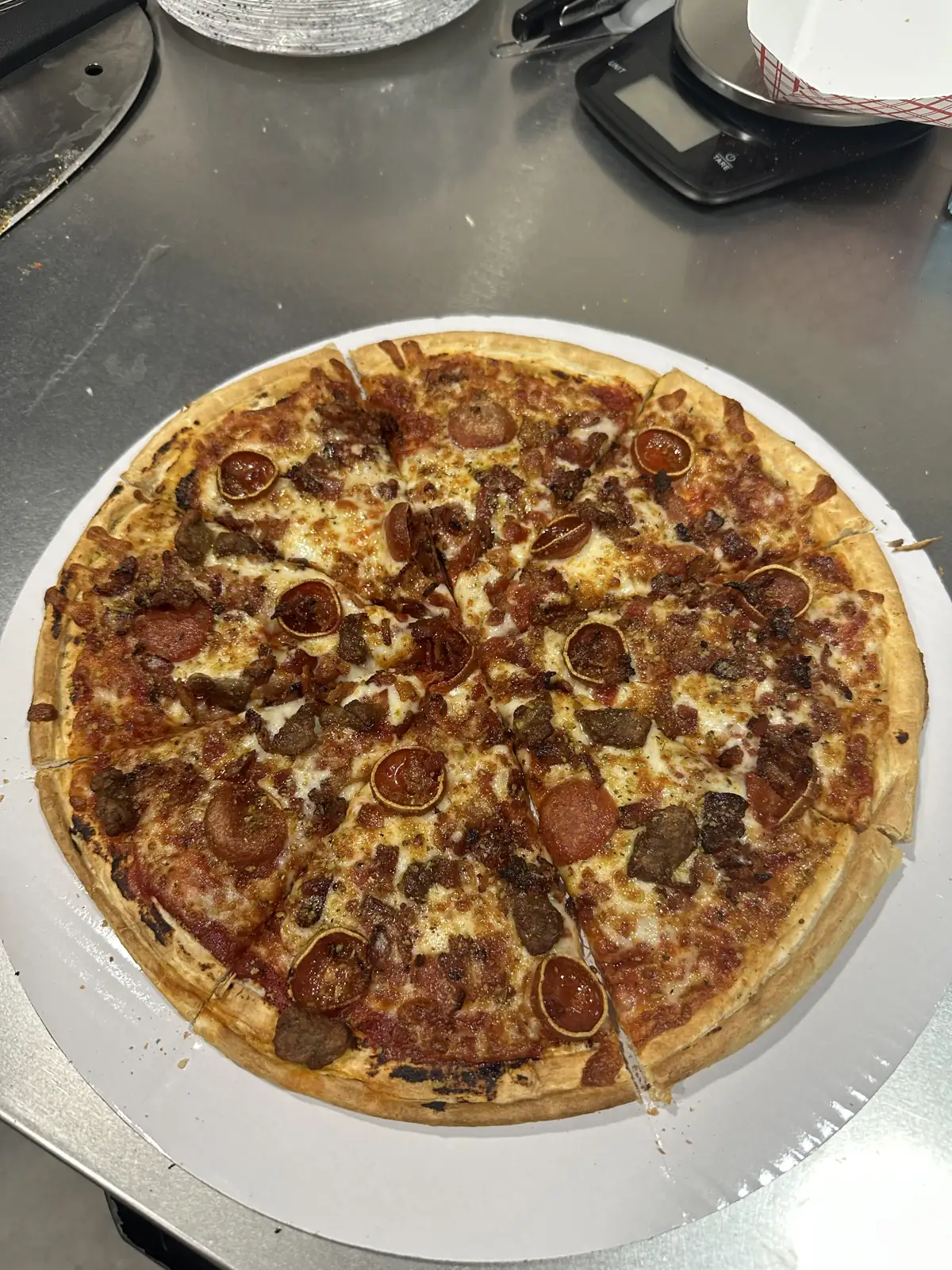 A sliced pizza topped with pepperoni and sausage on a round board