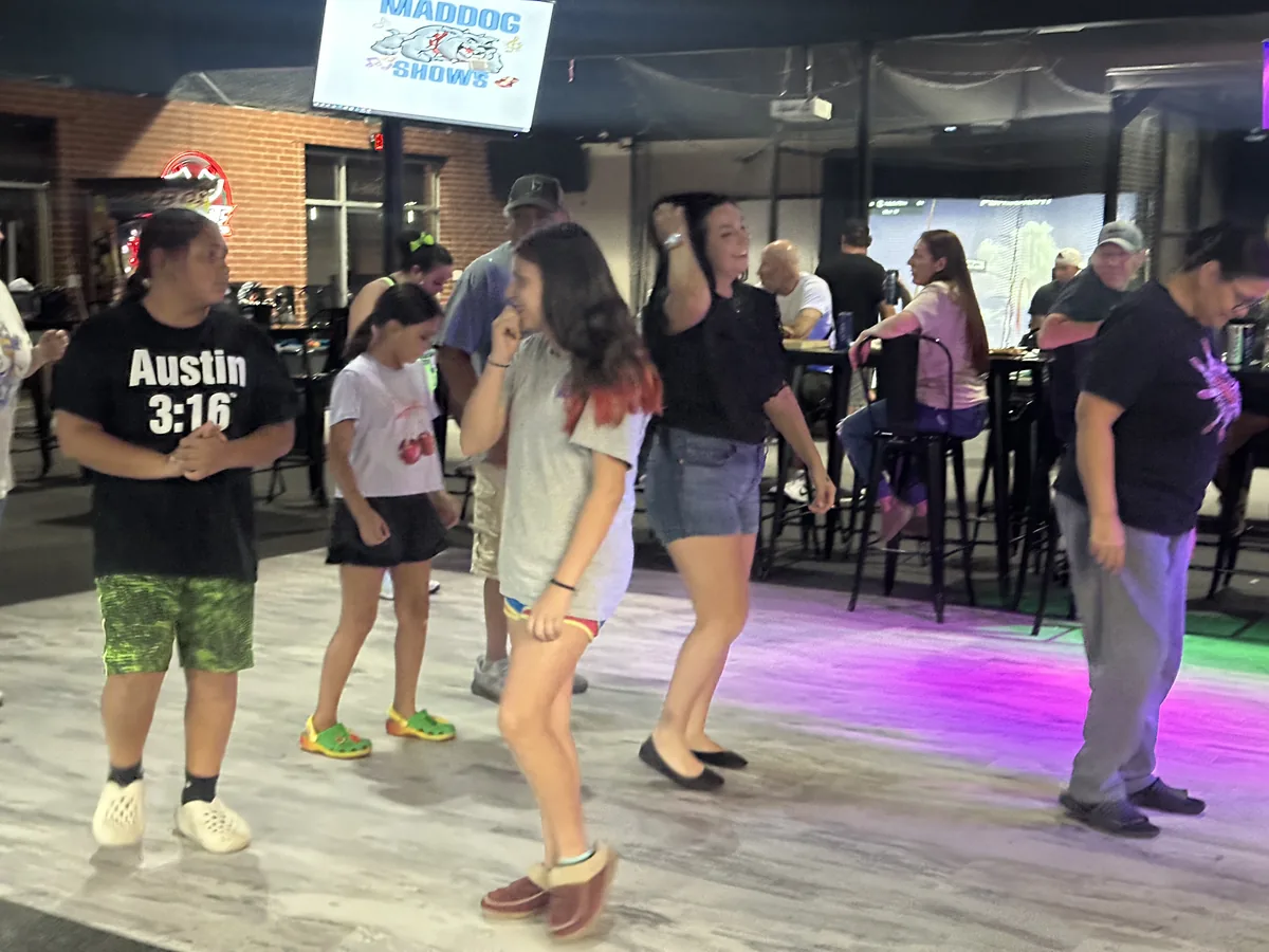 Kids and adults dancing on the Siege dance floor under purple and green lights